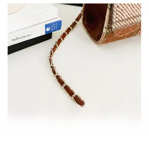 Close-up of vintage plaid fabric handbag with gold chain and brown leather strap