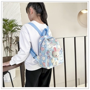 Dettaglio del charm con coniglietto e motivi a cuore su zainetto azzurro per bambini