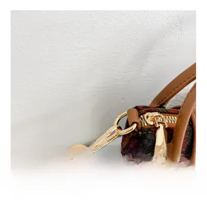 Detail of the golden detachable strap hook and wool plaid texture on a vintage bag
