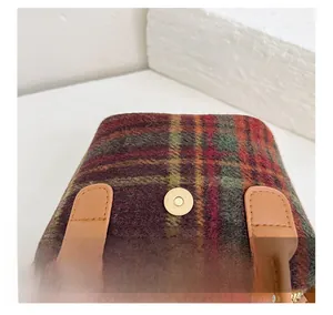 Close-up of retro plaid fabric texture with gold magnetic clasp and leather handle