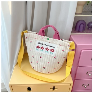 Détail du sac seau matelassé blanc avec imprimé cerise, poignée rose et sangle