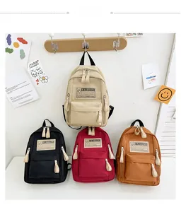 Détail de quatre sacs à dos en toile pour enfants avec poches et écussons tendance