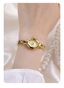 Close-up of elegant gold chain bracelet watch on wrist with satin and pearl background