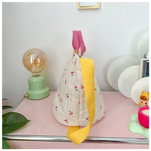 Détail d'un sac seau en coton matelassé avec motifs cerises et bandoulière colorée