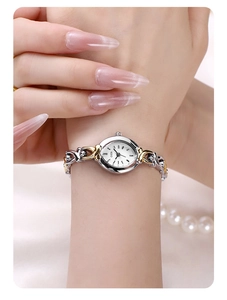 Detailed view of an elegant silver and gold oval quartz watch worn on a wrist