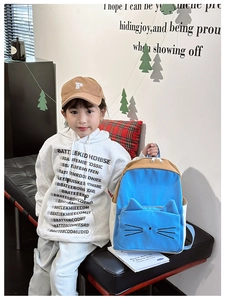 Detail of blue cat-shaped backpack with 3D ears and contrast color stitching on a child