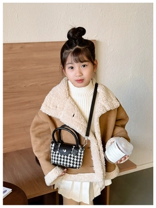 Dettaglio di una mini borsa da bambina con motivo pied-de-poule e tracolla nera