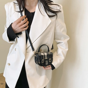 Mini sac bandoulière à carreaux noir et blanc avec boucles dorées porté sur un blazer
