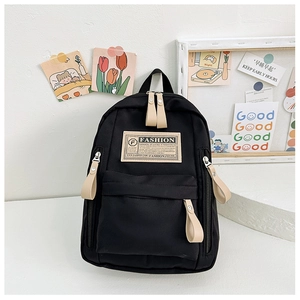Détail d'un sac à dos scolaire en toile noire avec des tirettes de fermeture beiges