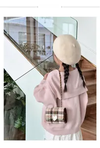 Detail of pink knitted cardigan and beige beret with a plaid heart crossbody bag