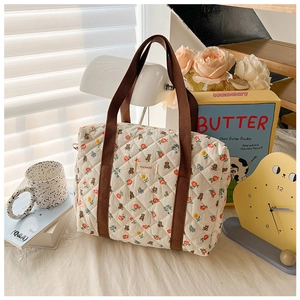 Detail of quilted cotton floral bag with bear pattern and brown handle in home setting
