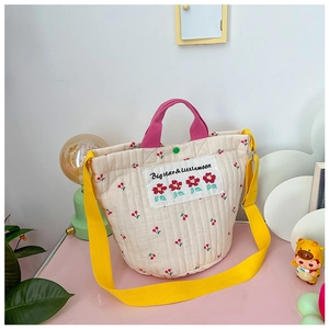 Détail du sac seau matelassé crème avec imprimé cerise et bandoulière jaune