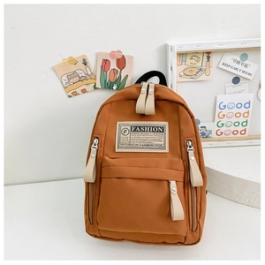 Gros plan détaillé du sac à dos en toile orange avec étiquette mode et poche zippée