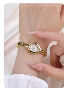 Detailed close-up of a vintage gold bracelet watch with an oval dial on white silk