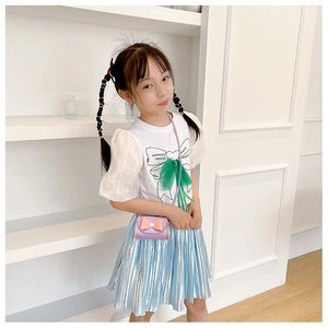 Girl wearing a purple mini crossbody bag with a pink bow accent for kids outfits
