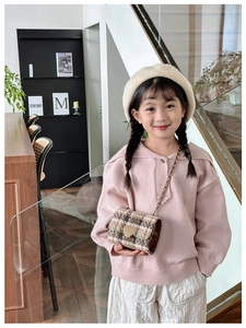 Detail of a child wearing a vintage plaid mini crossbody bag with a golden heart lock