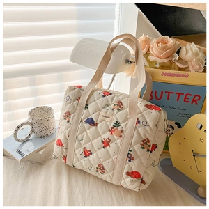 Detail of beige quilted tote bag featuring cute cartoon bear print and fabric handles