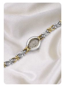 Macro shot of the elegant GEDI silver oval watch dial on a soft white silk background