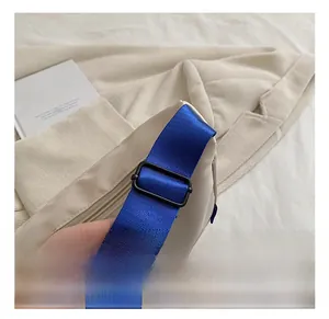 Detail of the adjustable royal blue woven shoulder strap on a beige canvas kids bag