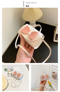 Detail view of an off-white mini crossbody bag with a large pink decorative bow in PU leather