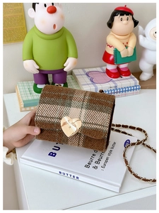 Close-up of brown plaid crossbody bag for girls with golden heart-shaped metal lock detail