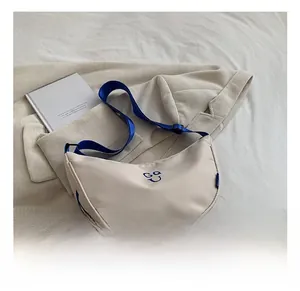 Detail of off-white crescent crossbody bag with blue logo and adjustable blue strap