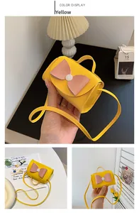Detail of yellow mini crossbody bag with a pink bow and a white round button buckle