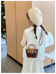 Detailed view of kids red plaid crossbody bag with brown leather handle and metal clips