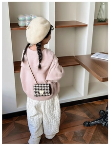 Close-up of a mini plaid crossbody bag with heart buckle styled with a pink knit sweater