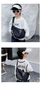Detail view of a black nylon semi-circle chest bag for kids with white graphic lettering