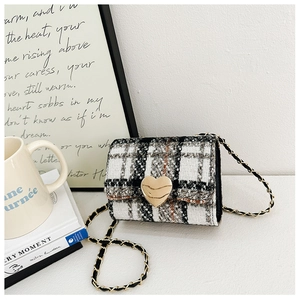 Detail of tweed checkered girls handbag with heart clasp and golden chain strap