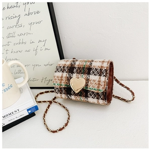 Macro detail of kids tweed plaid handbag with golden heart clasp and chain strap