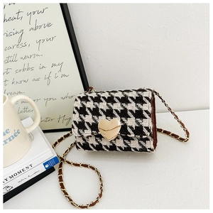 Detail of vintage houndstooth fabric pattern with golden heart buckle and chain strap