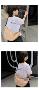 Detail of khaki crescent crossbody bag with white letters and adjustable black strap