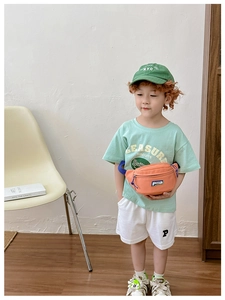 Detail of child wearing an orange canvas waist bag with zipper and logo in a studio setting