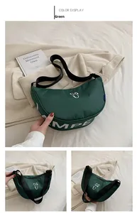 Detail view of a green crescent canvas shoulder bag with white lettering and adjustable strap