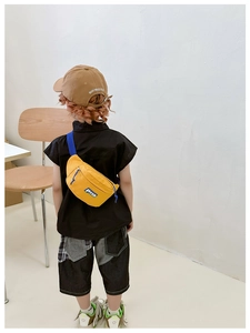 Detailed back view of a yellow canvas crossbody bag worn by a child in a casual style