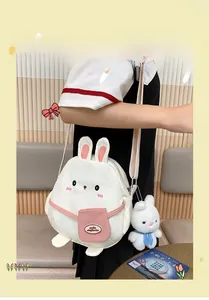 Detail of cute white rabbit crossbody bag with pink adjustable strap and plush charm