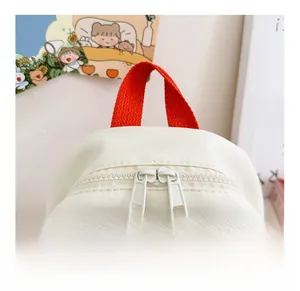 Detail of smooth double zipper closure and red handle on canvas kids backpack