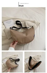Detail view of khaki half-moon canvas bag with adjustable strap and GQ print