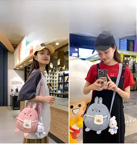 Close-up of cute cartoon rabbit plush crossbody bags in pink and blue with bunny charms
