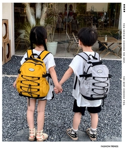 Rear view of children wearing durable drawstring canvas backpacks in yellow and grey