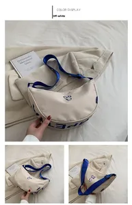 Detail of cream canvas crescent bag featuring blue GQ U logo and adjustable strap