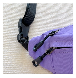 Detail of lavender purple canvas belt bag featuring double zippers and black buckle