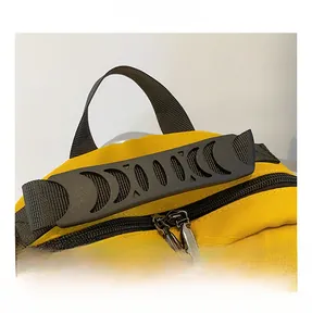 Detail of yellow canvas backpack showing the ergonomic black handle and metal dual zippers