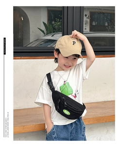 Detail of black canvas kids chest bag featuring an oval PEACE badge and sturdy buckle