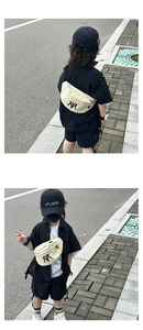 Outdoor street style shot of a cream canvas kids fanny pack with black NY embroidery