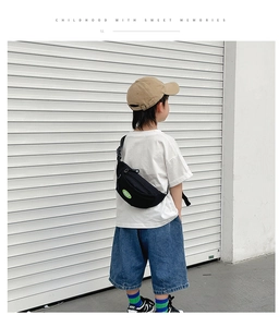Rear view of child wearing black canvas sling bag with green Peace patch and adjustable strap