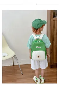 Detail of child wearing a lightweight contrast canvas backpack in green and beige