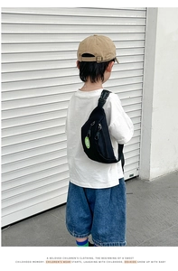 Detail of kids black canvas chest bag with green PEACE patch and double zipper compartments